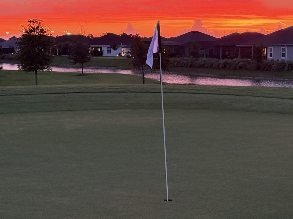 Sunset over a golf course green lined with homes in the Village of Shady Brook, The Villages, Florida